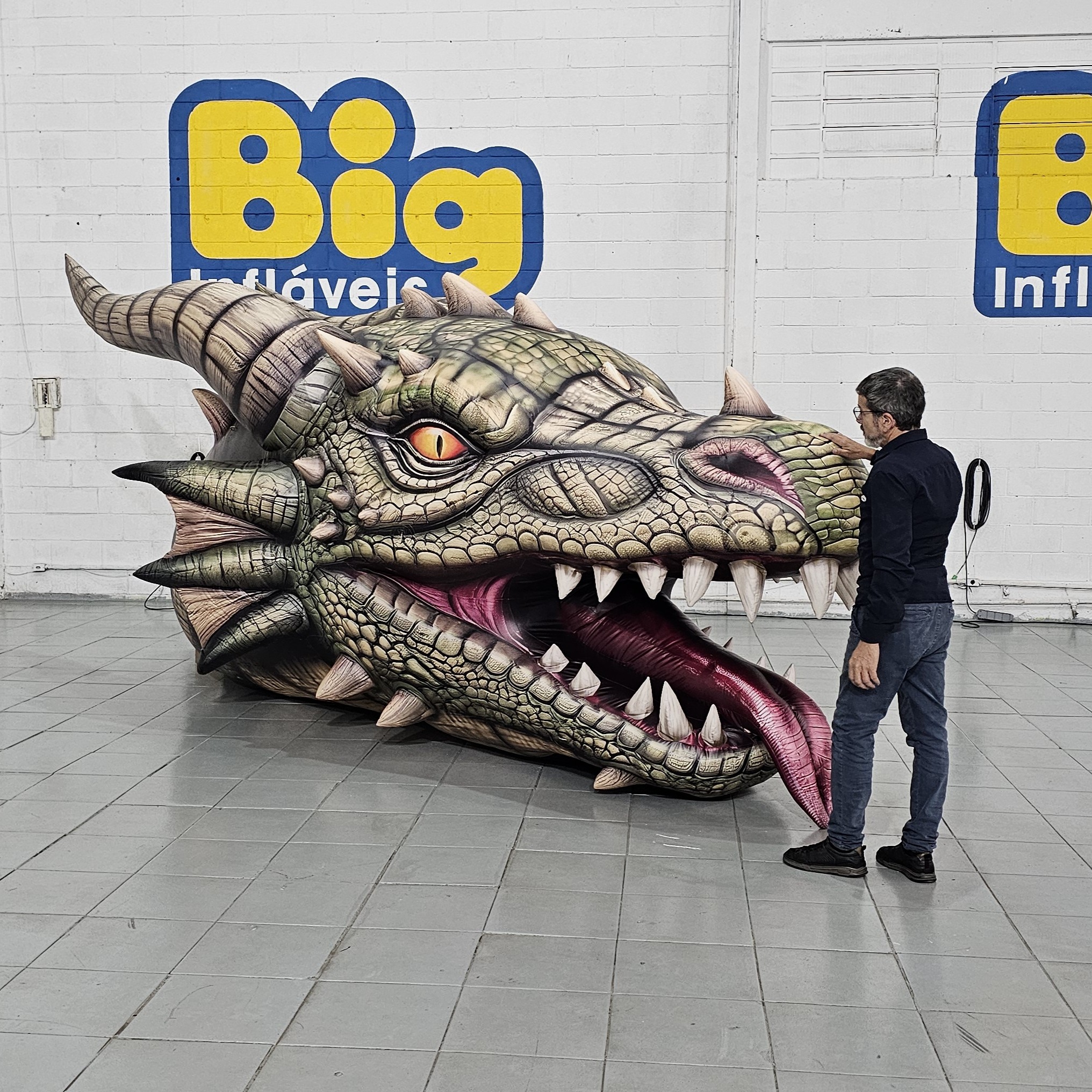 Dragão inflável completo ao lado de uma pessoa para comparação de escala